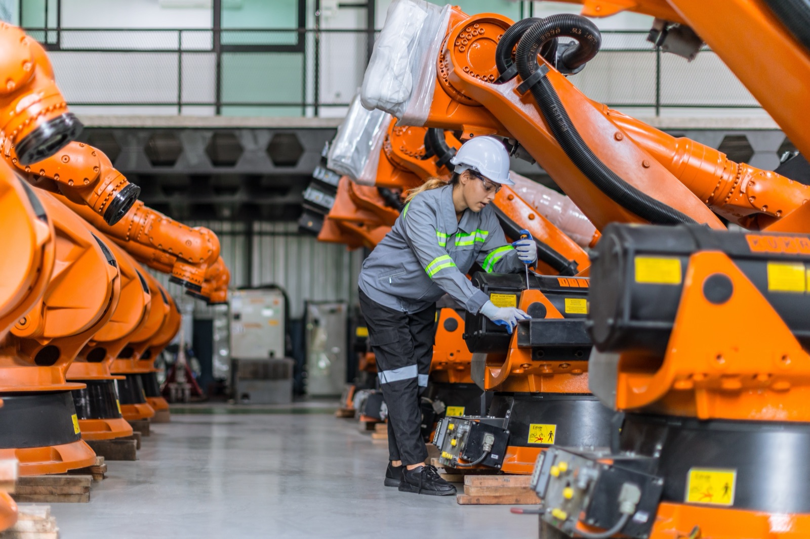 Technician servicing industrial robotic arms on the production floor
